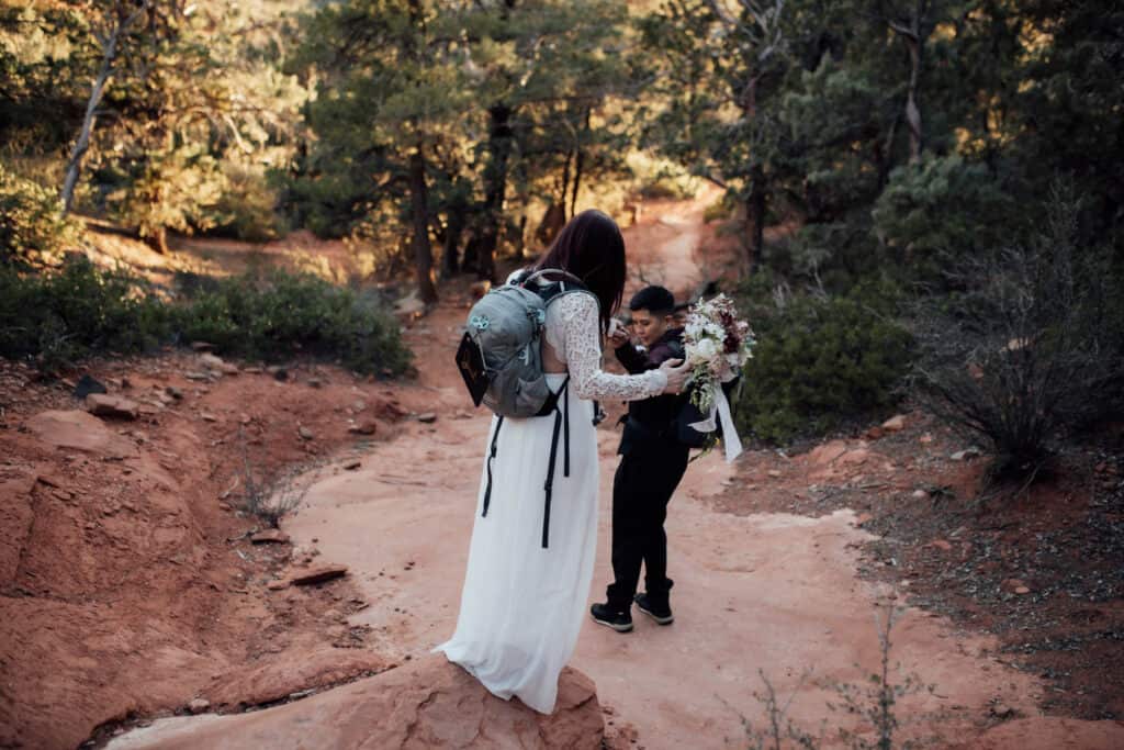 A couple in wedding clothes hiking to their ceremony location on their elopement day.