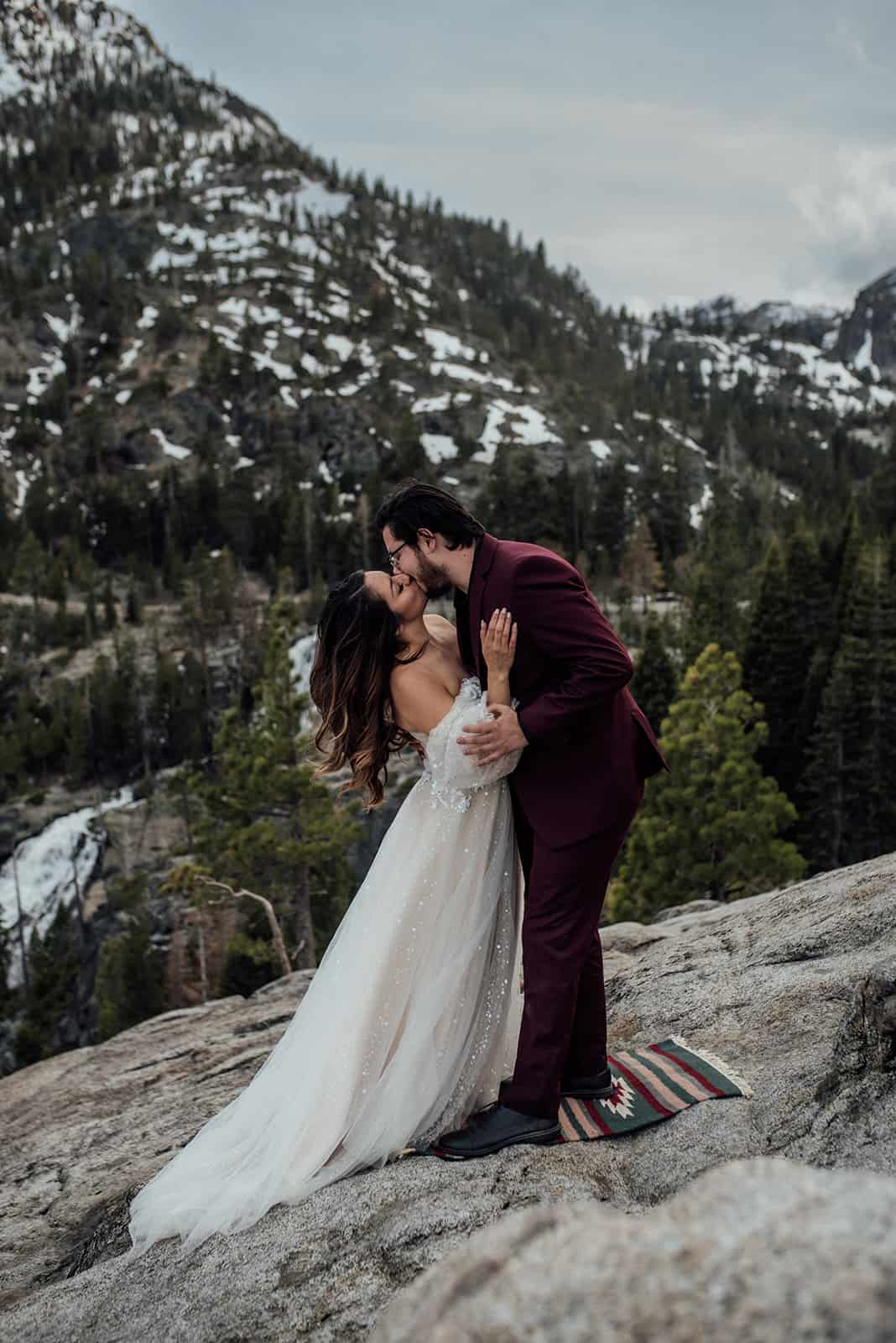 elopement couple kissing with snowy mountains behind