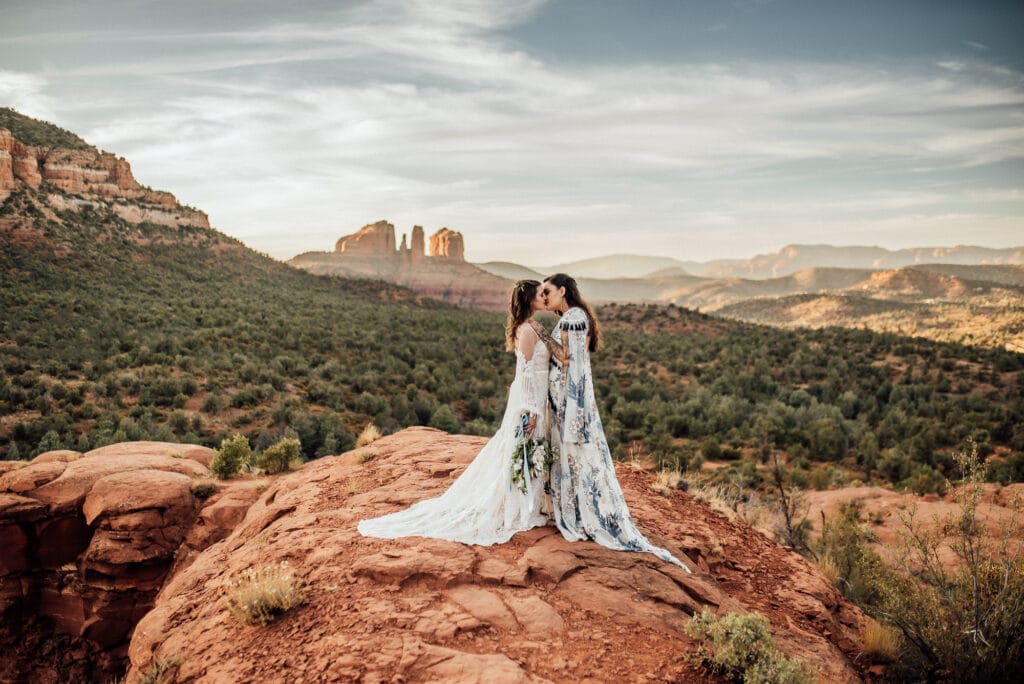 lgbtqia+ elopement couple on the red rock cliffs in Sedona, AZ with Cathedral Rock vista behind.